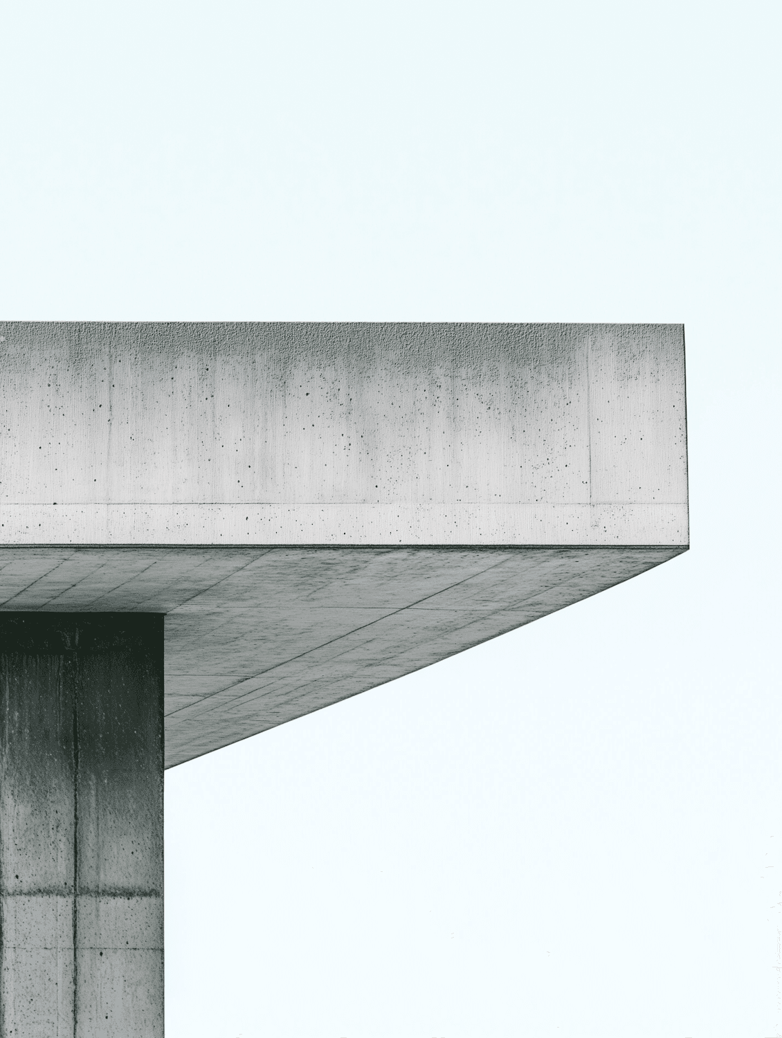 Minimal concrete building with sharp lines against a pale sky